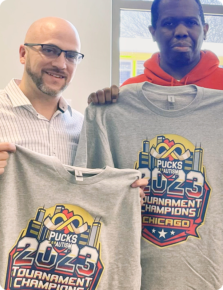 Two HB Threads employees holding up custom printed shirts for Pucks for Autism